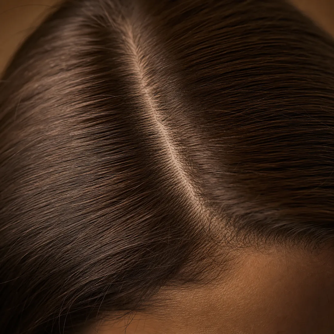 Close-up of a part line in brown hair, density visible right at the scalp