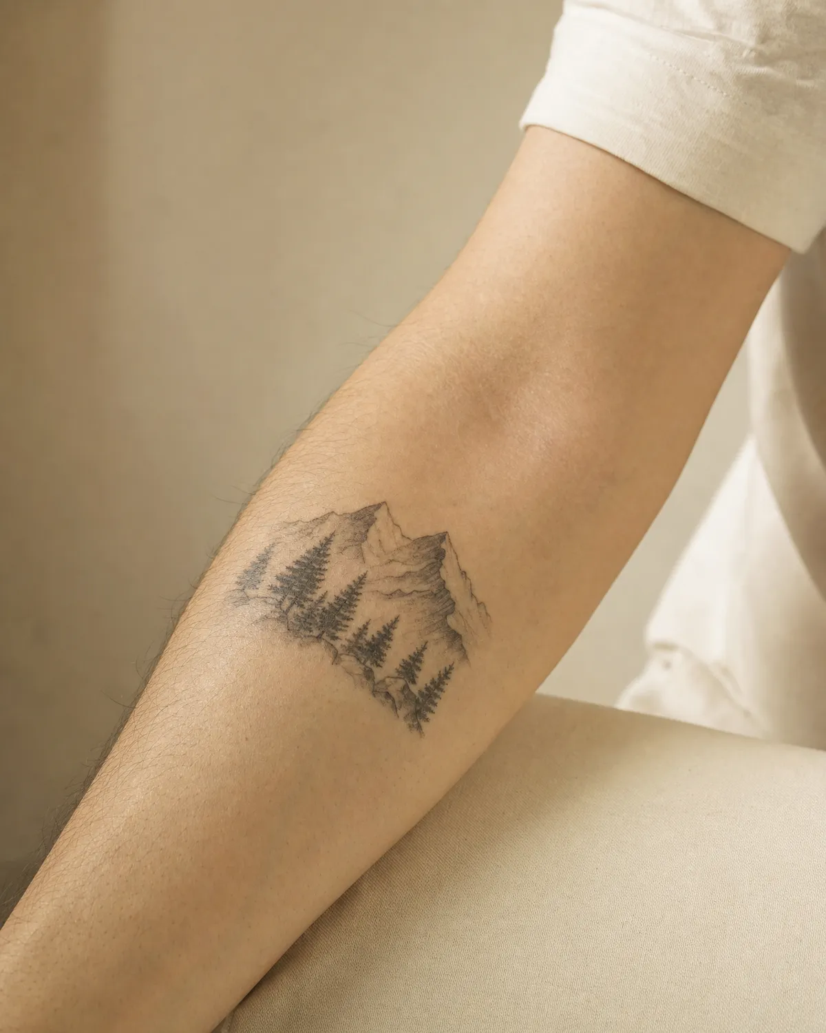 Un tatouage de paysage de montagne en noir et gris sur l’intérieur de l’avant-bras.